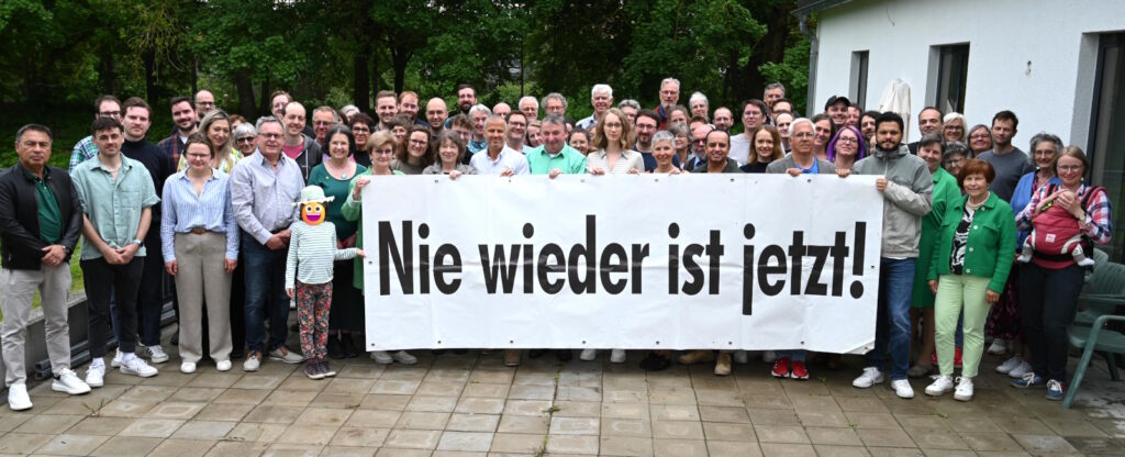 70 Mitglieder des GRÜNE Bezirk Schwaben hinter einem Transparent mit der Aufschrift "Nie wieder ist jetzt"