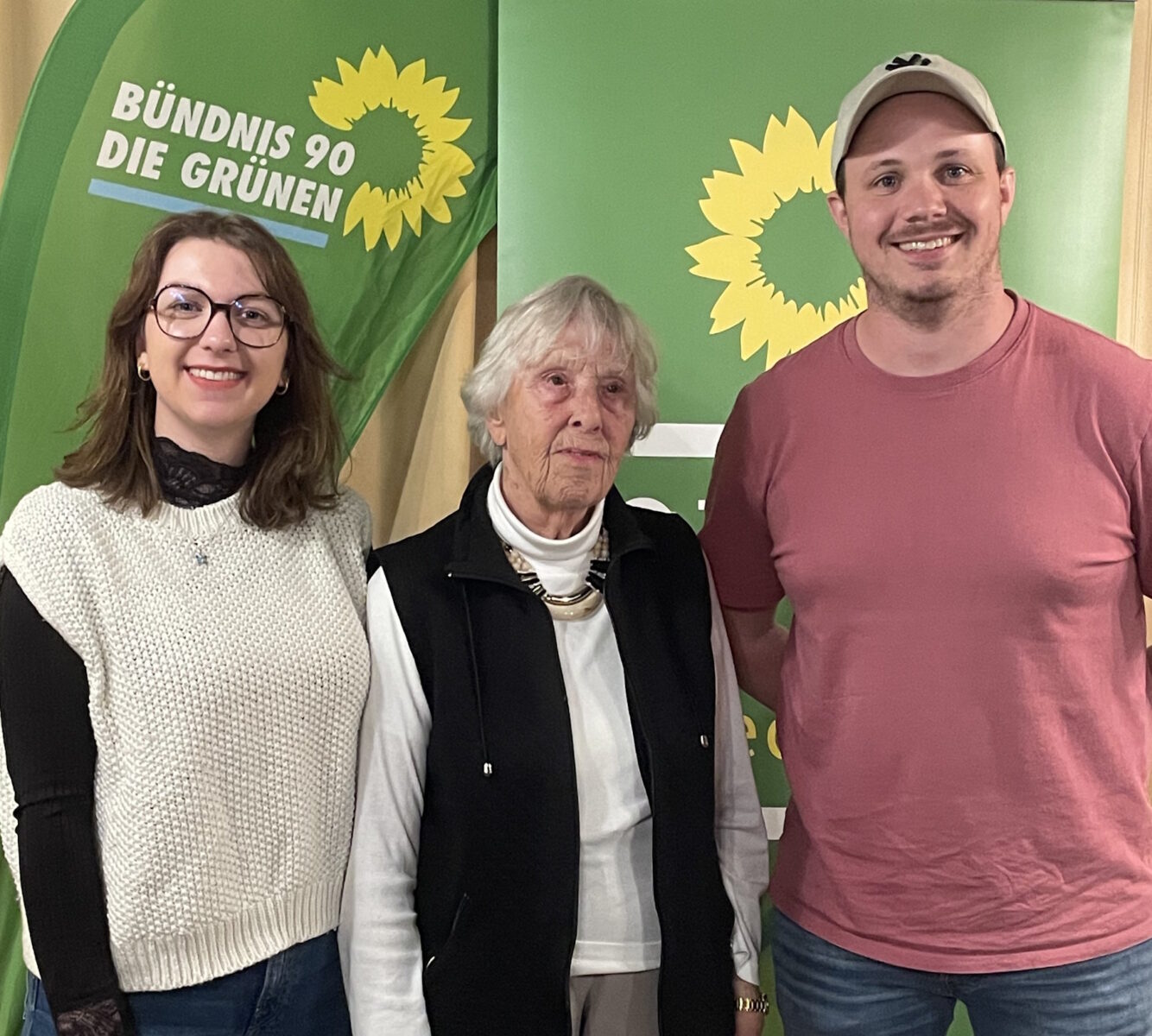 Personen vor grünen Parteibannern: von linke - Lena Eichner, Christine Baier und Christopher Mayer