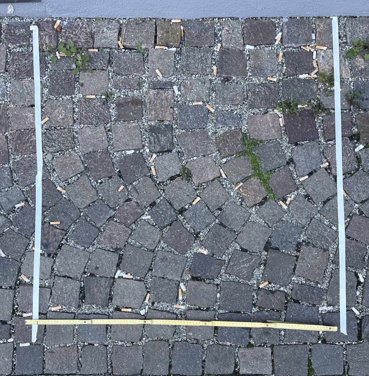 Foto auf dem die Anzahl der  Zigarettenstummel auf einem Quadratmeter Boden gezeigt wird.