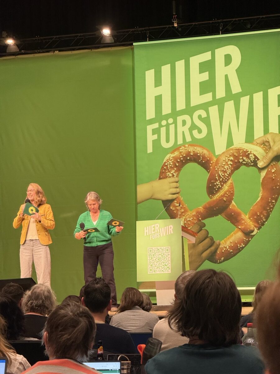 Eva Lettenbauer und Gisela Sengl auf der Bühne. Im Hintergrund der Bühne der Slogan "Hier fürs Wir"